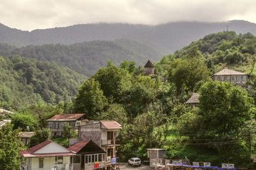 Fototapeta na wymiar Mountain village gosh with houses and chapel of St. Sarkis covered with fog, located in the woods near the town of Dilijan 