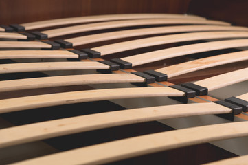 Close-up wooden elements of an arthopedic base of a double bed. Interior structure of furniture