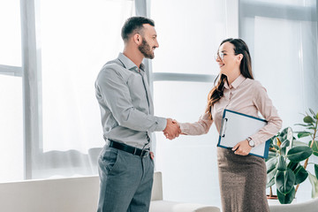 smiling psychologist and patient shaking hands in office