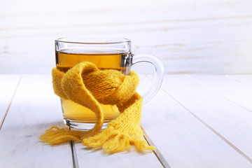 Healing glass of tea in a scarf on a wooden background