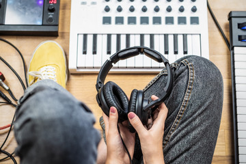 Young woman holding studio headphones, point of view shot. Top view of female musician at home...