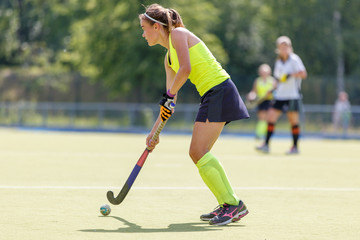 Naklejka premium Young hockey player woman with ball in attack playing field hockey game