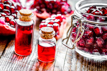 sliced pomegranate and extract in glass on wooden background