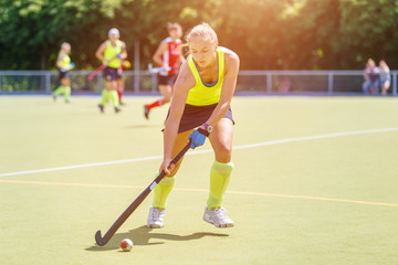 Obraz premium Young hockey player woman with ball in attack playing field hockey game