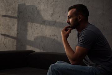 upset thoughtful man sitting on sofa