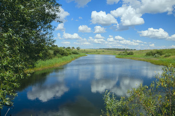Sunny summer landscape with river,fields,green hills and beautiful clouds in blue sky.River Upa in Tula region,Russia.