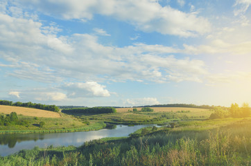 Sunny summer landscape with river,fields,green hills and beautiful clouds in blue sky.Tula region,Russia.
