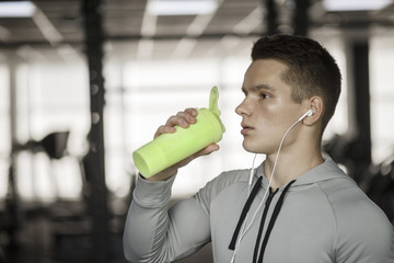 Young guy drinks sports nutrition in gym