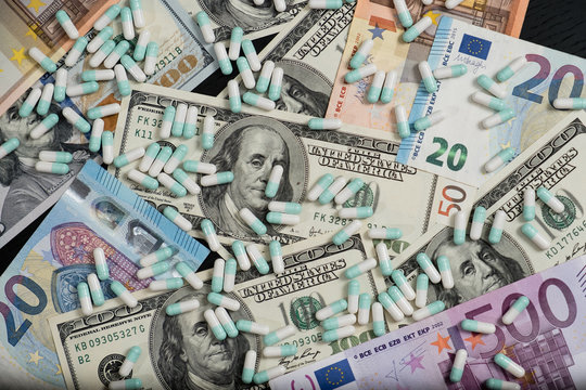 A bunch of pills and tablets on euro and dollar banknotes