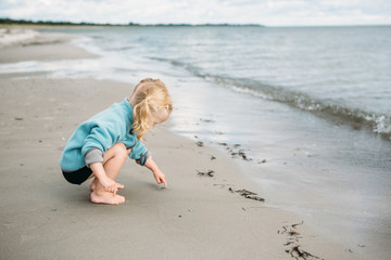 2 year old picking up a little jelly fish