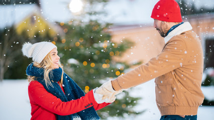 Beautiful Young Couple Dance and Spin in the Backyard of their Idyllic House while Snow Fall Romantically. Happy Young People in Magical Winter Time.
