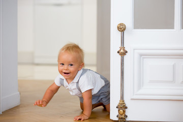 Little cute baby child, boy, crawling from behind a door © Tomsickova
