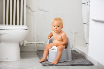 Child sitting on potty. Kid playing with educational toy and Toilet training concept. Baby learning, development steps. - obrazy, fototapety, plakaty