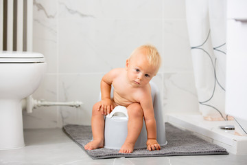 Child sitting on potty. Kid playing with educational toy and Toilet training concept. Baby learning, development steps. - obrazy, fototapety, plakaty