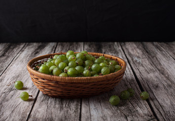 berries of gooseberries in a basket on a wooden background