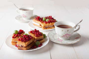 Viennese waffles with berries and a cup of tea stand on the table