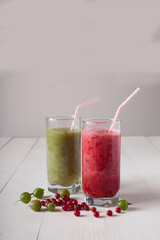 smoothies of red currants and gooseberries stand on a white wooden table