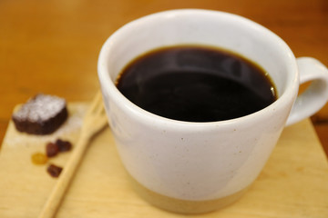 Hot black coffee in a white cup on wooden tray, selective focus and blurred background 