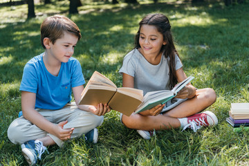 cute little kids sitting on grass and reading books