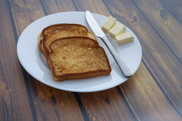 bread toast and several slices of butter on a plate on a wooden background