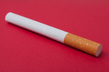 closeup of isolated cigarette on red paper background