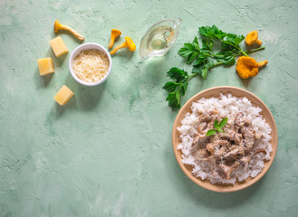 Risotto with mushrooms chanterelles on a plate on a wooden white table.
