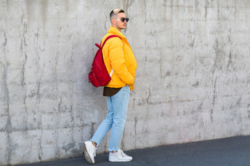 Obraz na płótnie Canvas fashion guy standing near a concrete wall in yellow clothes