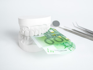 The denture with tooth money in euros on white backgrund