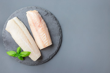 Fresh raw cod fillet with basil on stone plate, horizontal, copy space, top view © iuliia_n