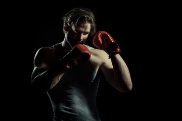 Boxing, young boxer on black background. Sexy guy in red sports gloves. Sport concept