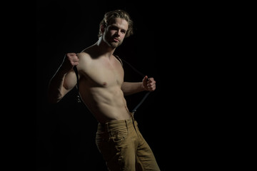 Sexy man played with his suspenders for trousers on a black background. Seductive fashionable and sensual man