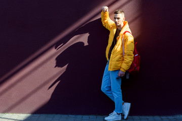 fashion guy standing near a viola wall in yellow clothes
