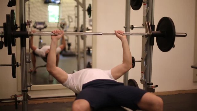 Man training in gym. Male preparing and doing bench press with bar.