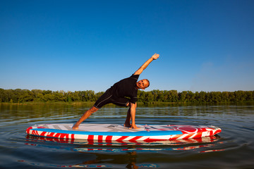 Man practicing yoga on a SUP board during sunset