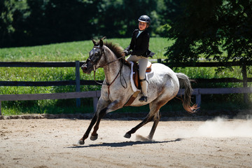A girl riding a horse while competing in a horse show.