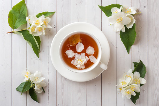 Mug of herbal tea with petals of Jasmine flowers on a light background.