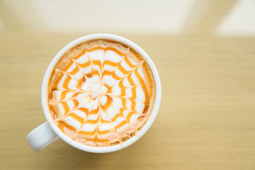 Hot Macchiato coffee with caramel in white cup on wood table