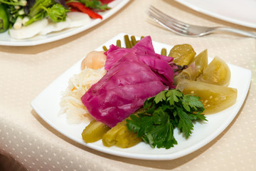 Тарелка с соленой капустой, чесноком, огурцами, перцем, помидорами, стручковой фасолью и свежей петрушкой, закуска к водке