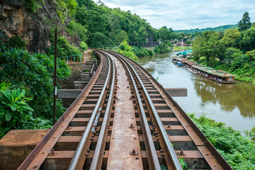 Old railroad tracks on bridge beside cliff rock