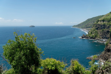 Obraz premium Rocky coast with high cliffs, sea coast, ocean, mountains, sea, beach, sky, clouds. Bali, sea surf with breaking waves on the coast, Indonesia. Ocean with waves and rocky cliff.
