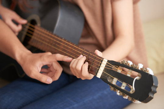 Cropped image of young woman attending acoustic guitar class