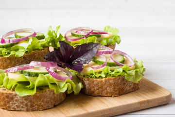 Open sandwiches with cheese, cucumbers and onions on wheat bread. Selective focus.