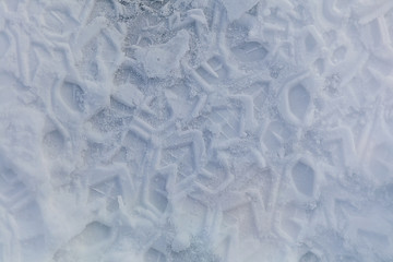 Traces of rough soles on snow background
