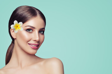Fototapeta na wymiar Cheerful Young Woman Smiling. Cute Girl with Makeup and Flower on Background with Copy space