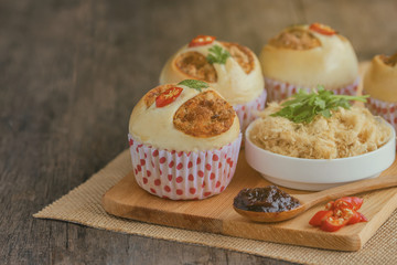 Homemade cup of soft and sticky bun with dried shredded pork or pork floss and shrimp roasted chili paste on wood table with ingredients. Thai style delicious bread with sweet and spicy taste.