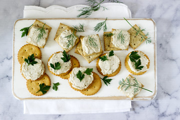 Snack from crackers and curd fish paste with herbs on a light background.