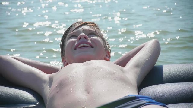 A young guy is swimming in the sea on an inflatable mattress. Positive emotions. Hot summer day