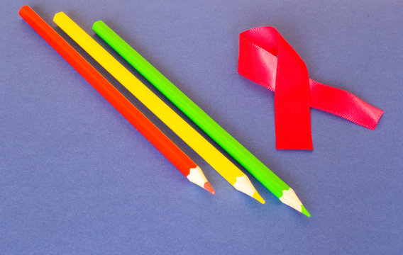 Color pencils and pink ribbon on a blue background