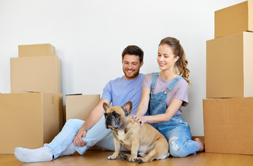 mortgage, people and real estate concept - happy couple with boxes and french bulldog dog moving to...