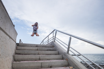 Happiness concept with young beautiful girl jumping with joyful against a white sky blue background. sea side place